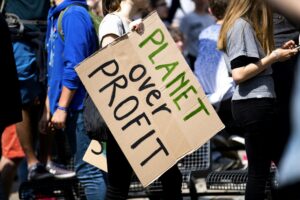 Youth climate protest with participants holding 'Planet Over Profit' sign.